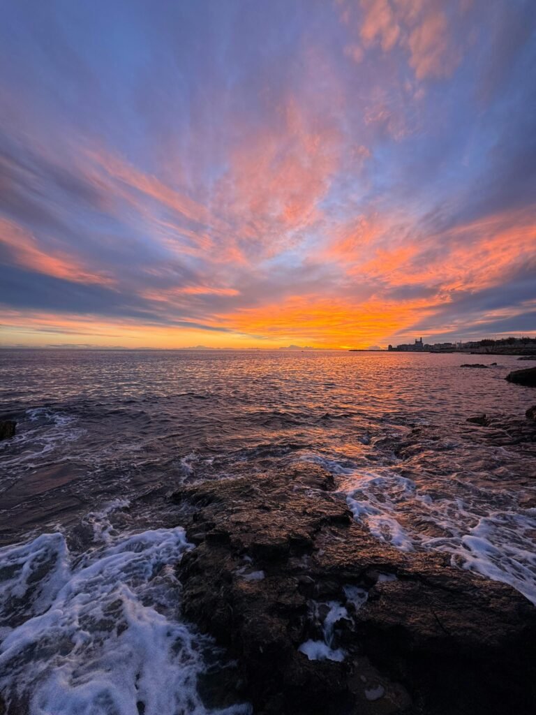 Captivating sunrise over the Italian coastline with vivid colors and dramatic clouds.